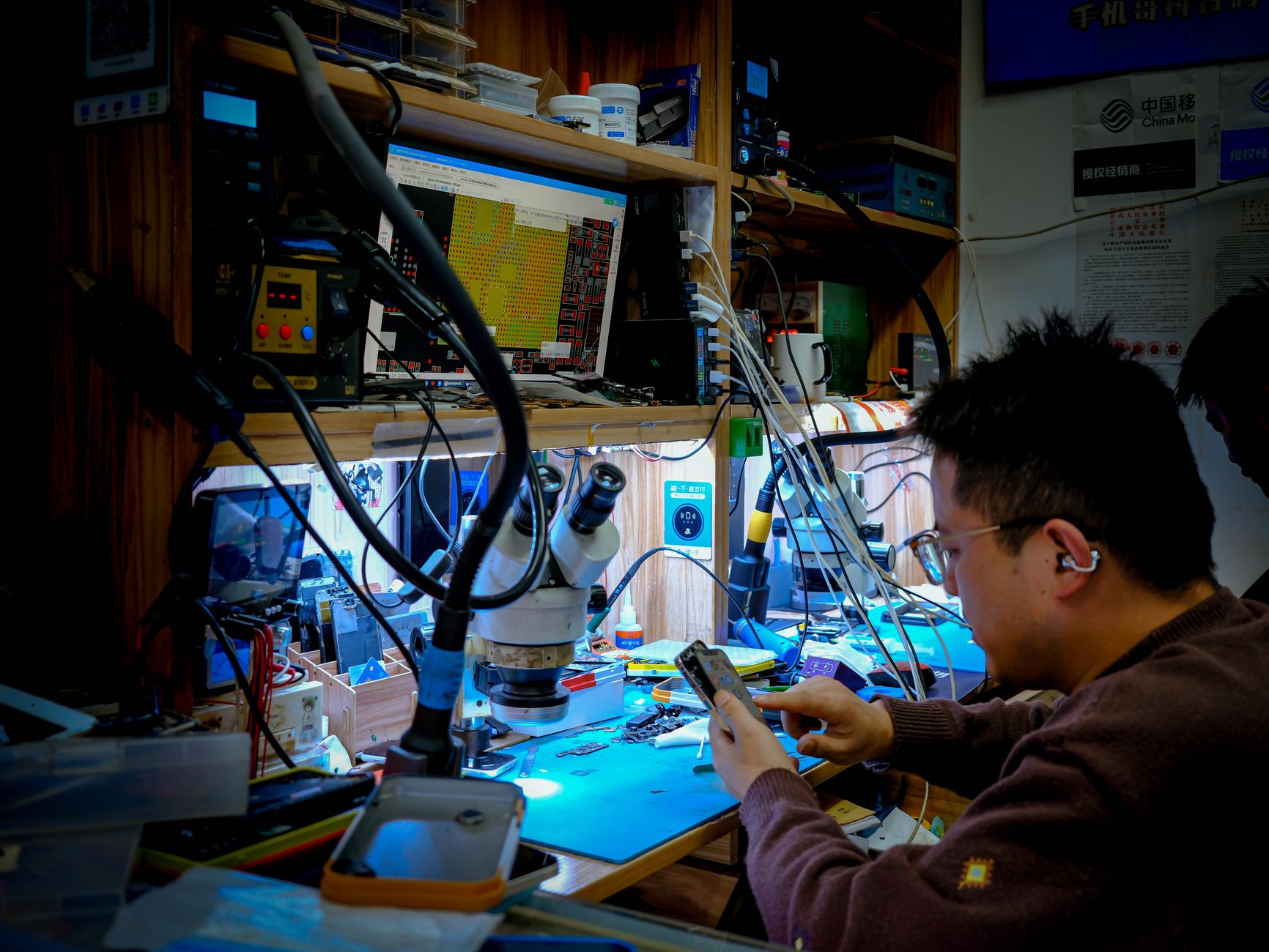 Técnico realizando reparo de tela de iPhone em bancada profissional